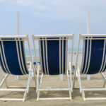Three beach chairs facing the sea